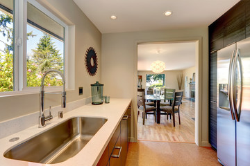 Modern small new kitchen with large sink and white countertops.