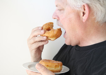 older man eats glazed doughnut