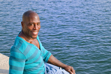 Fototapeta na wymiar Muscular black man relaxing with the seaside in the background.