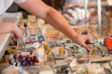 Unrecognizable male supermarket worker with cheese closeup