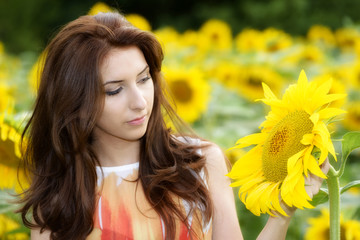 Naklejka premium young beautiful woman on blooming sunflower field in summer