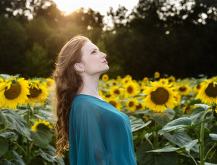 Naklejka premium young beautiful woman on blooming sunflower field in summer