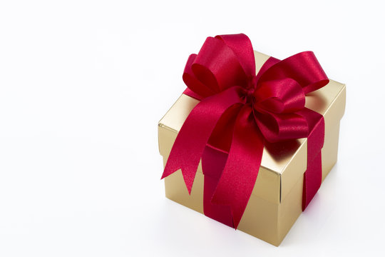 Beautiful gold present box with red bow and ribbons