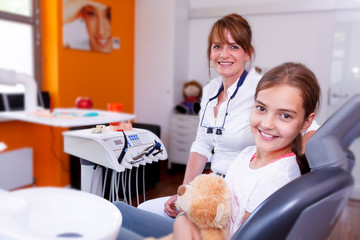 A doctor and teenager girl in a dentist surgery smiling in the c