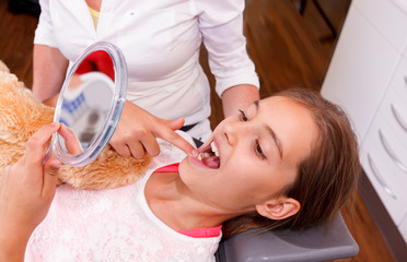 A doctor explains a young girl how she can care the teeth.