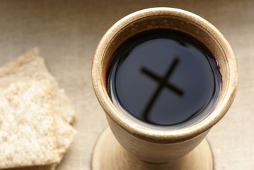 Chalice with wine and bread. Cross shadow in the chalice.