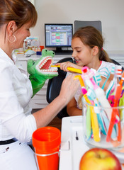 A dentistry woman doctor plays brushing teeth with a young girl 