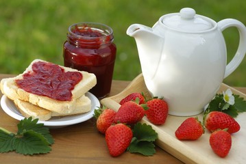 Mug, toast, glass with strawberry jam and strawberries
