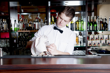 Young handsome bartender working  in front of the bar.
