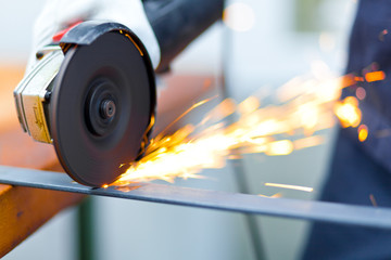 Worker using a grinder on a metal plate