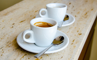 Two white espresso cups standing on the marble table