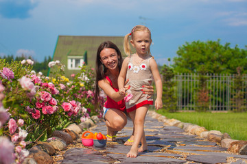 Young mother with her cute daughter have fun in the garden