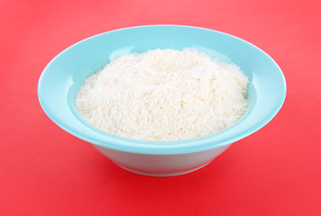Fototapeta na wymiar Powdered milk in bowl for baby on red background