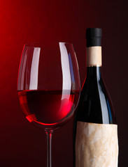 Glass of wine  with bottle on bright red background