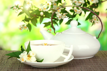 Cup of tea with jasmine, on bamboo mat, on bright background