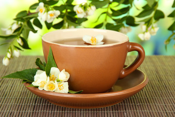Fototapeta na wymiar Cup of tea with jasmine, on bamboo mat, on bright background