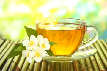 Cup of tea with jasmine, on bamboo mat, close-up