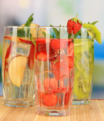 Glasses of fruit drinks with ice cubes on table in cafe