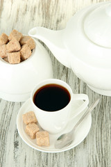 Cup of coffee, teapot and sugar-bowl on color wooden background