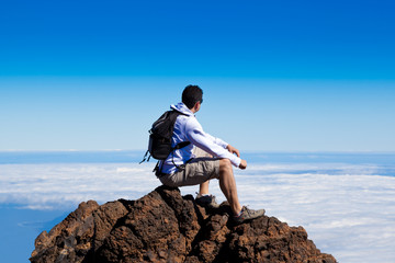 Fototapeta na wymiar Young Man Having a Rest in a High Peak Over Clouds