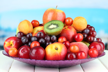 Assortment of juicy fruits on wooden table, on bright