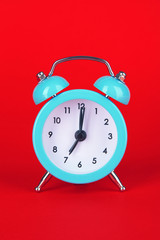 Blue alarm clock on red background