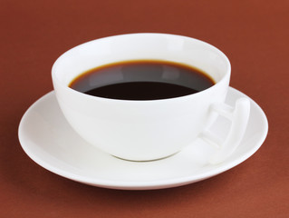 A cup of strong coffee on brown background