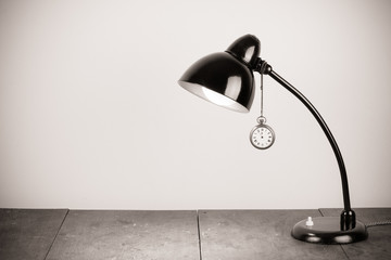 Retro black table lamp and pocket watches hanging on it