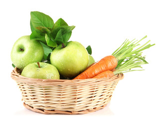 Juicy green apples and carrots with leaves in basket, isolated