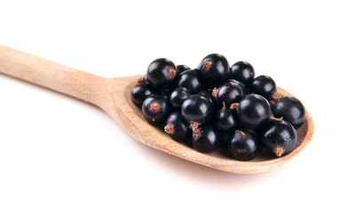 Black currant in wooden spoon isolated on white