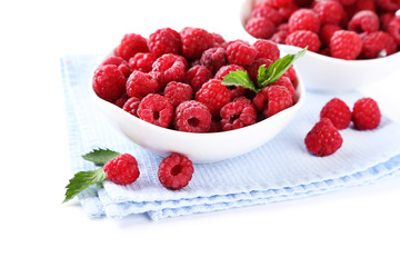 Ripe sweet raspberries in bowls, isolated on white