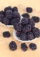 Sweet blackberry in bowls on wooden table