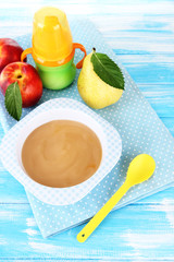 Tasty baby fruit puree and baby bottle on wooden table