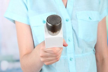 Female with microphone on room background
