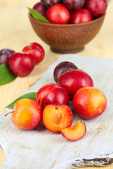 Fototapeta na wymiar Ripe plums on wooden table close-up