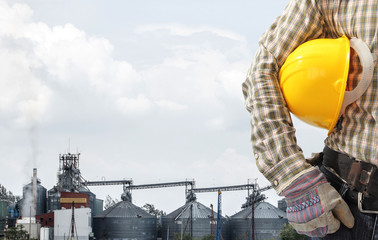 technician at work against corn dryer silos and blue sky backgro © thanapun