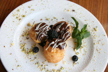 Profiteroles with berries on white plate