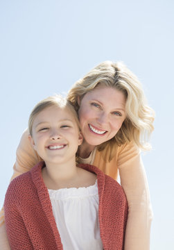 Mother And Daughter Smiling Together Against Clear Blue Sky