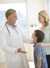 Doctor Explaining Woman About Son's Health In Clinic