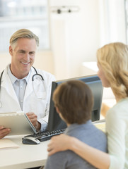 Doctor Explaining Report To Mother And Son In Hospital