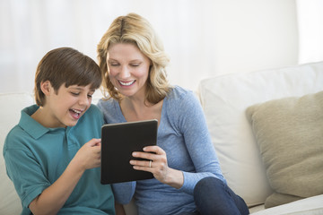 Woman And Son Using Digital Tablet Together On Sofa