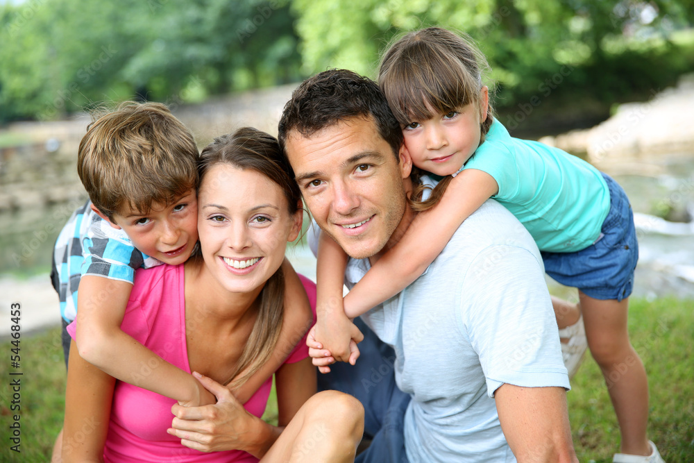 Poster Family relaxing by river in countryside