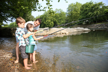 Fototapeta na wymiar Man teaching kids how to fish in river