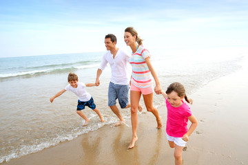 Happy family running on the beach