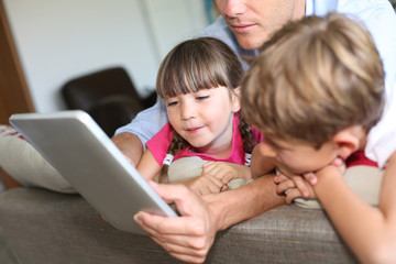 Father and children playing with tablet at home