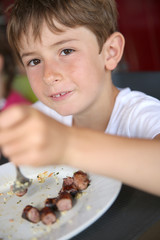 Portrait of young kid eating grilled food in summer