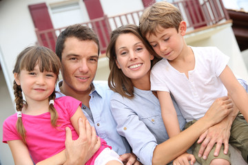 Happy family standing in front of new home
