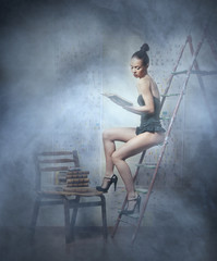 A young woman in lingerie reading a book on the ladder