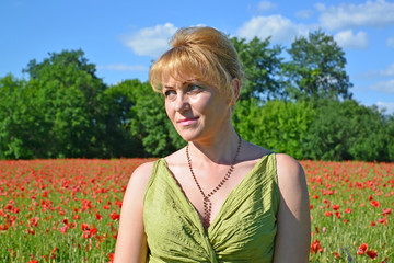 Portrait of the woman of average years in a poppy field