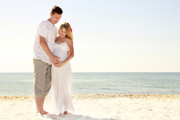 Pregnant couple in love on the beach